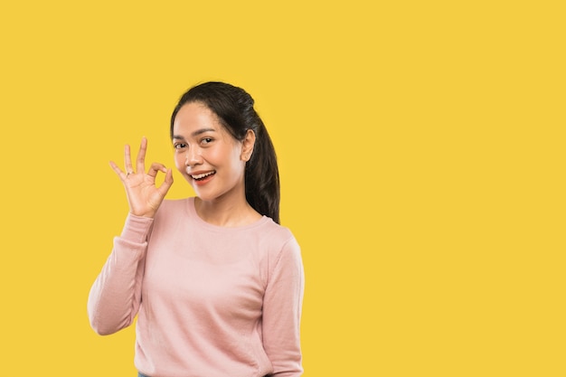 Attractive asian woman smiling with okay hand gesture while looking at camera