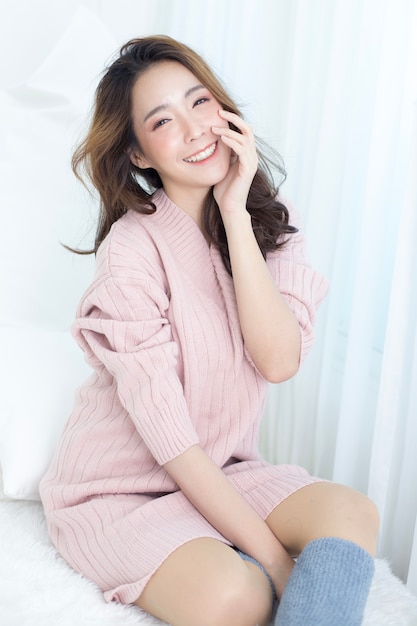 La donna asiatica attraente sveglia sul letto con emozione felice