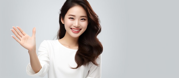 Attractive Asian woman in white shirt smiling with open hands on white background looking for copy space