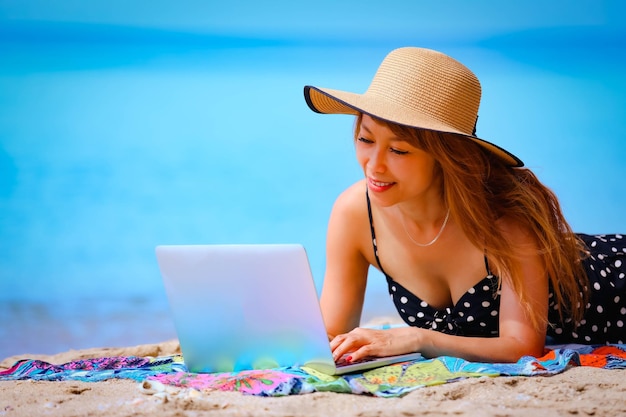 Attractive asian woman working on laptop on the tropical beach holidays and vacation concept