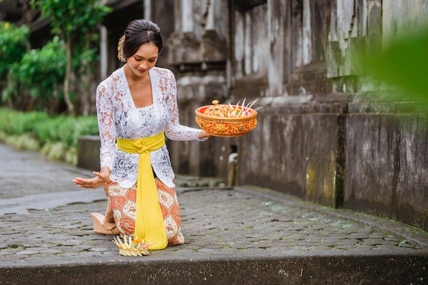 Attractive balinese woman in kebaya do prayer and make an offering to god in the morning