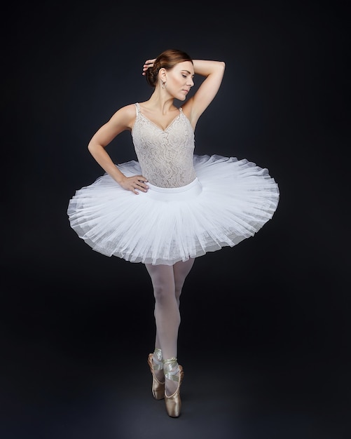 Attractive ballerina poses gracefully  on a black background