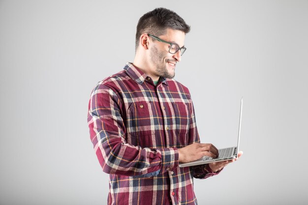 Attractive bearded man holding laptop computer isolated on gray