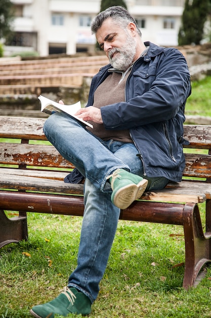 魅力的なひげのある男、公園で読む