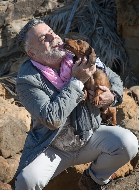 Attraente uomo barbuto in riva al mare con bassotto, cane