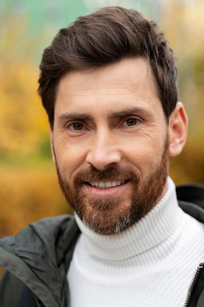 Attractive bearded man smiling confidently outdoors closeup view