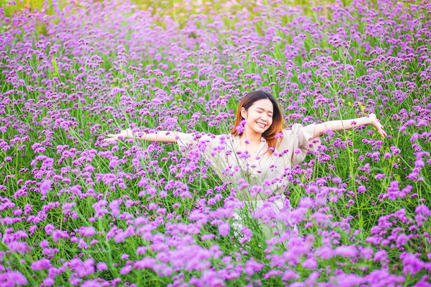 사진 매력적인 아름다운 여성이 꽃밭 한가운데서 행복의 자유를 느끼며 팔을 들어 올립니다.