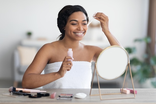 Attractive black woman applying beauty product after shower