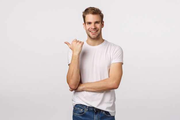 Attractive blond bearded man in white T-shirt pointing aside