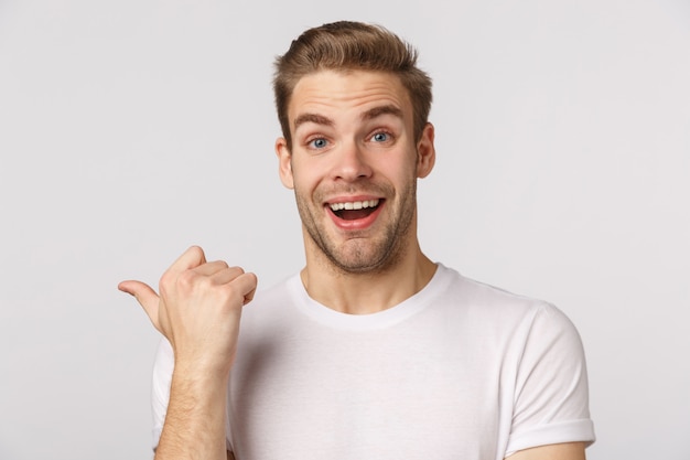 Attractive blond bearded man in white T-shirt pointing to the side