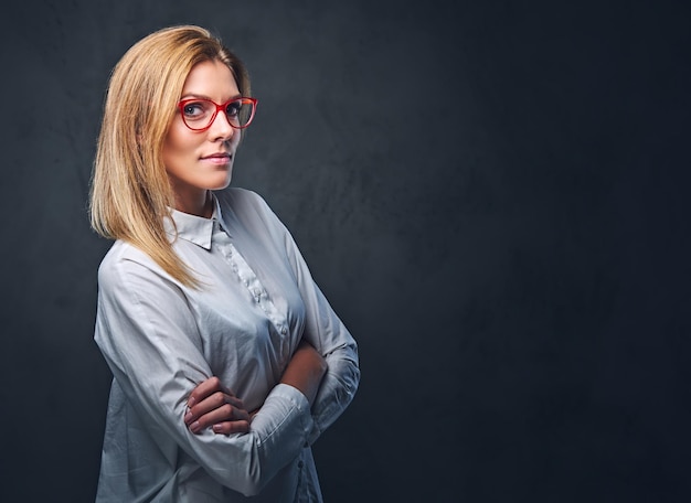 Attractive blond business woman in a white shirt, eyeglasses and crossed arms over grey background.