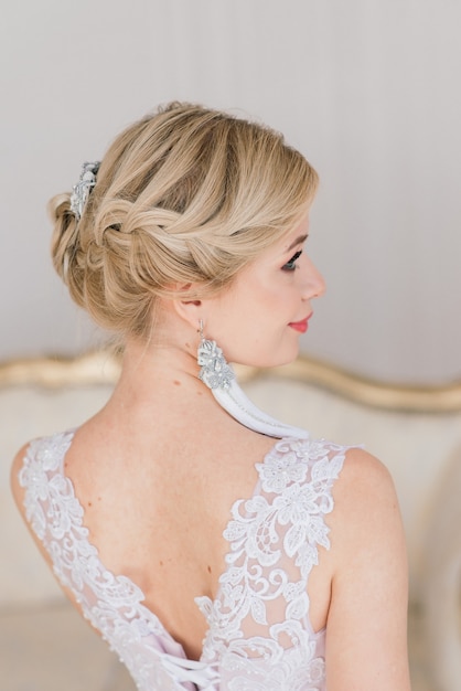 Фото Привлекательная блондинка невеста стоит у окна в белом интерьере в винтажном стиле.