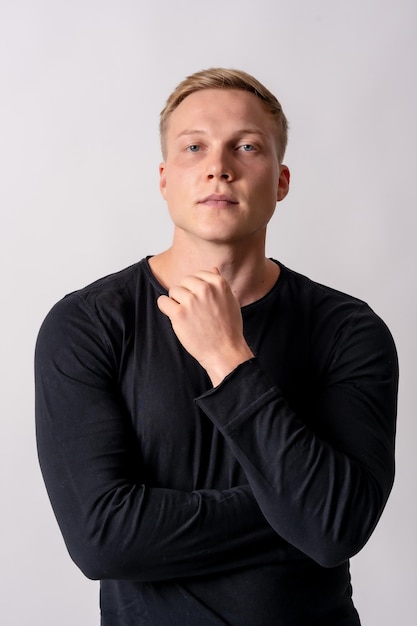 Attractive blonde german model in a black sweater on a white background looking at the camera seriously