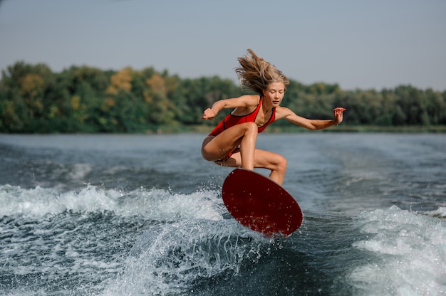 Attractive blonde girl jumping on the red wakeboard