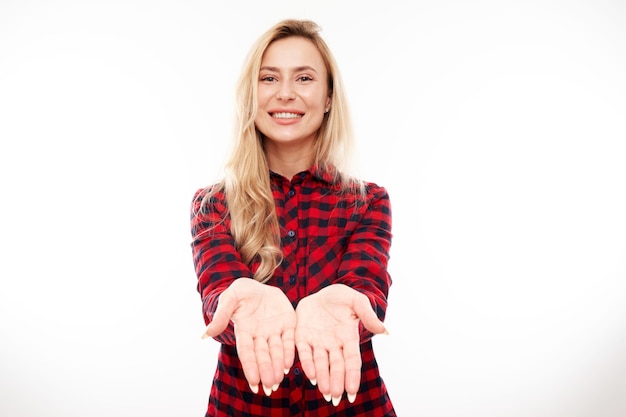 Attractive blonde girl promoter holding something in hand demonstrating empty space with excited face isolated on white background