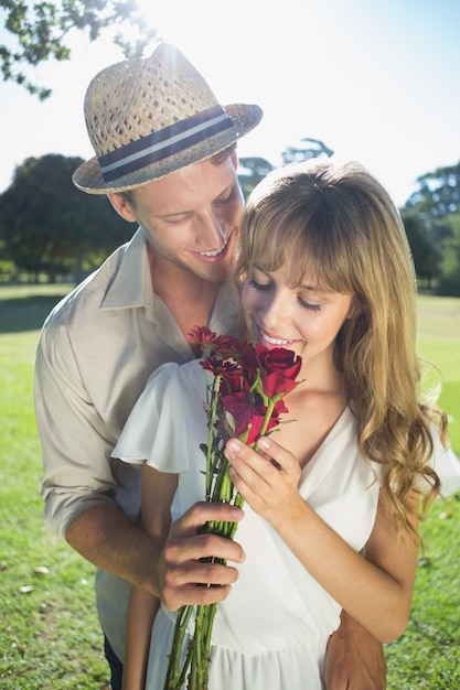 Attractive blonde smeling roses standing with partner