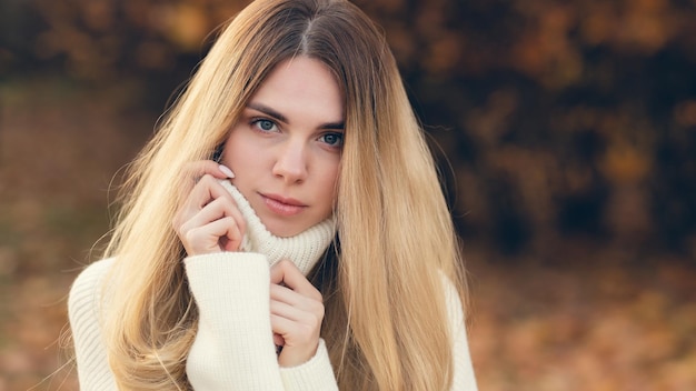 Attractive blonde in a white sweater on a background of autumn colors