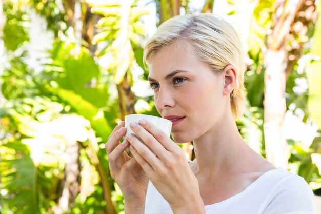 ホットドリンクを飲む魅力的なブロンドの女性