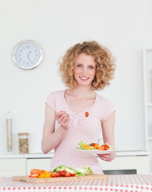 Привлекательная женщина блондинка есть овощи на кухне