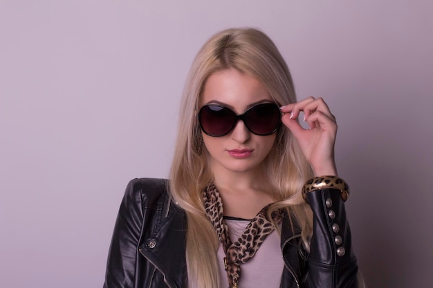 Attractive blonde woman in a glasses and leather jacket. Studio shot