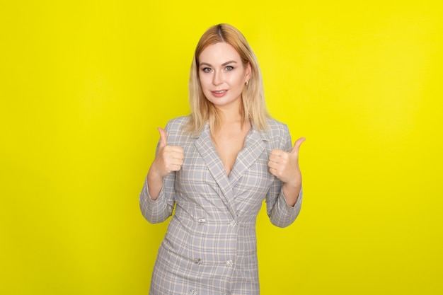 Attractive blonde woman in plaid jacket dress over yellow