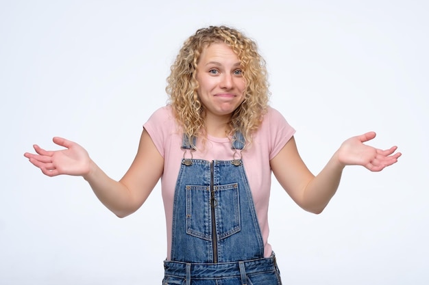 Attractive blonde woman shrugging her shoulders I do not know how it happened