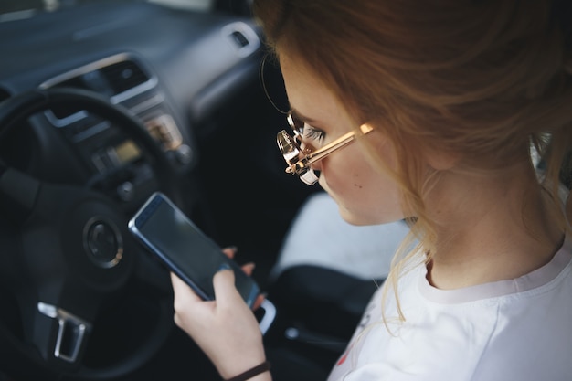운전하는 동안 그녀의 휴대 전화에 메시징 매력적인 금발 여자 문자.