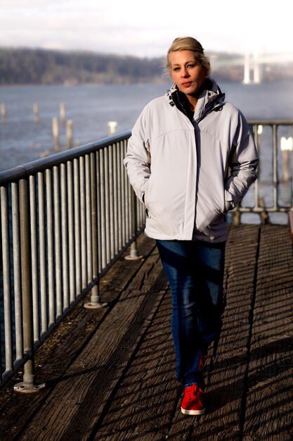 Photo attractive blonde woman walking along the waterfront