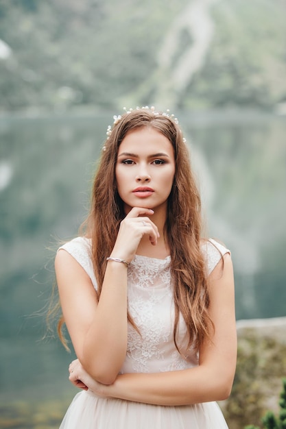 Attractive brunette bride in gorgeous white wedding dress standing near the lake Morskie Oko