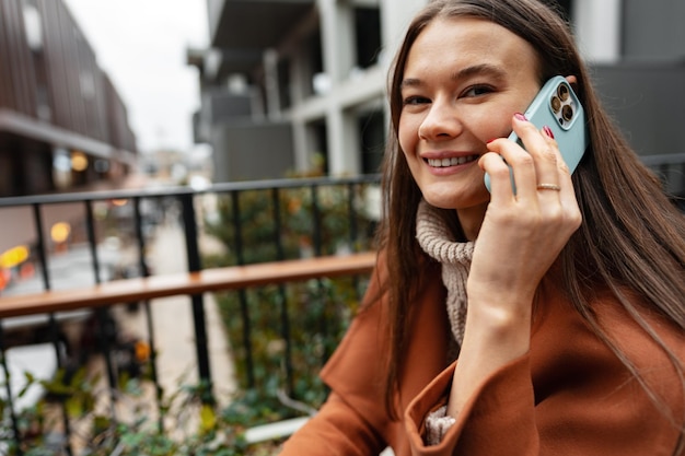 Donna di affari castana attraente che parla sul telefono cellulare nella via