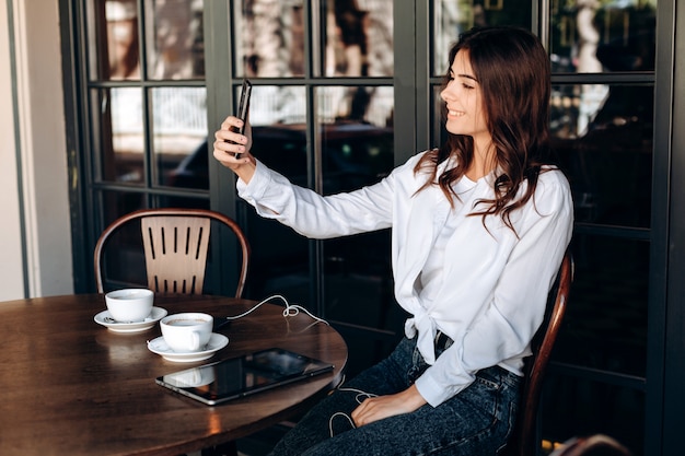 カフェで魅力的なブルネットはselfiesになります