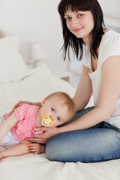 Attractive brunette female posing with her baby lying on her