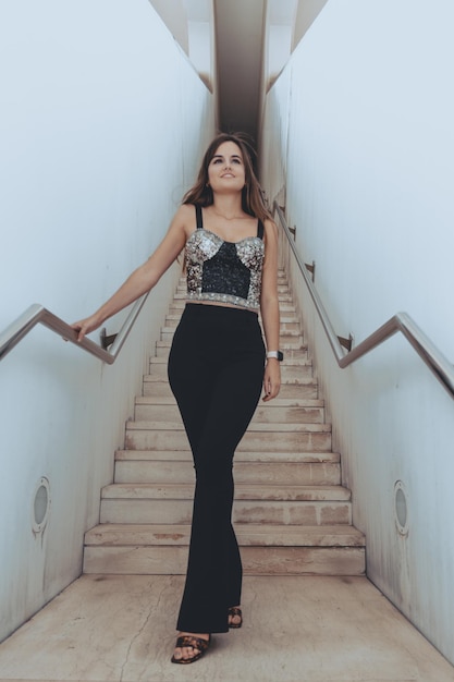 Attractive brunette girl with a perfect figure posing in front of the stairs inside the building