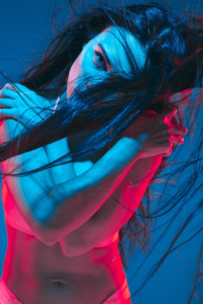 Attraente modella bruna su sfondo blu studio in luce al neon