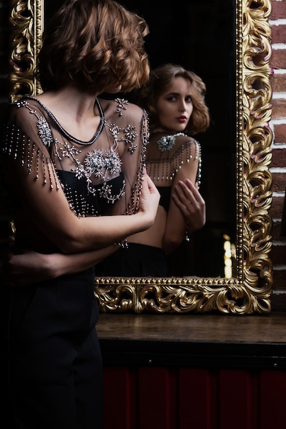 Привлекательная брюнетка модель носит бюстгальтер, глядя в зеркало