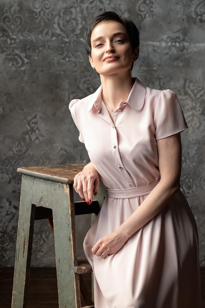 Attractive brunette woman in long pink vintage dress poses on camera