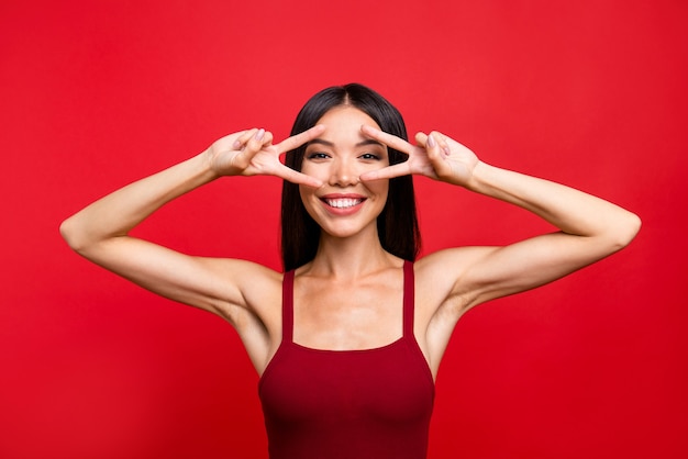 Attractive brunette woman in a red dress posing against the red wall