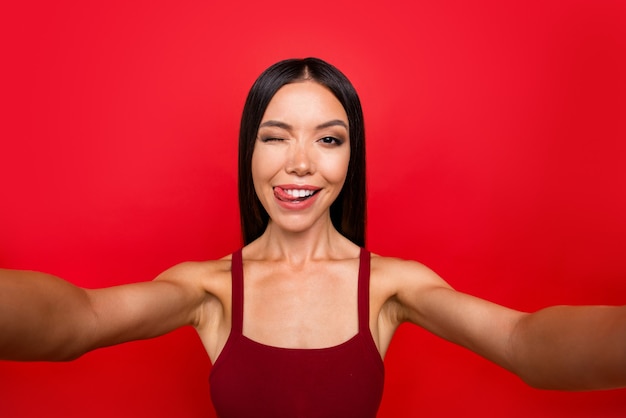 Attractive brunette woman in a red dress posing against the red wall