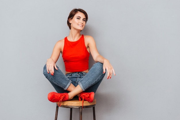 Attractive brunette woman sitting on the chair over gray background