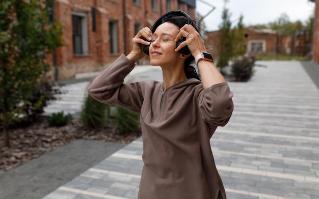 Attractive brunette woman with closed eyes puts headphones