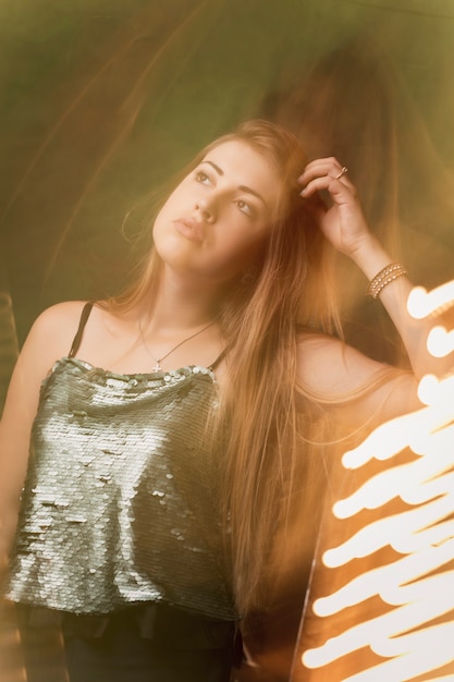 Привлекательная брюнетка молодая женщина позирует в темной студии со смешанным светом