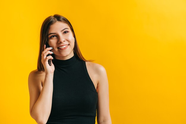 Attractive brunette young woman talking with someone using mobile phone and smiling