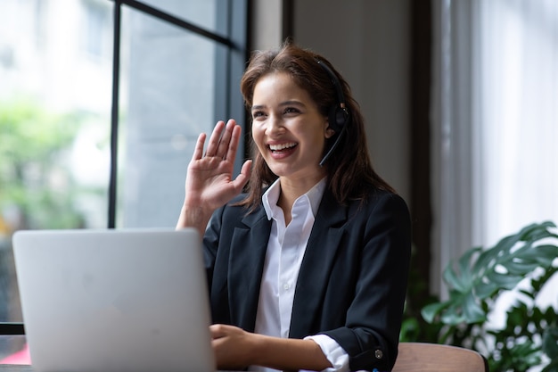 Attractive business woman Asian in suits and headsets are smiling while working with computer  