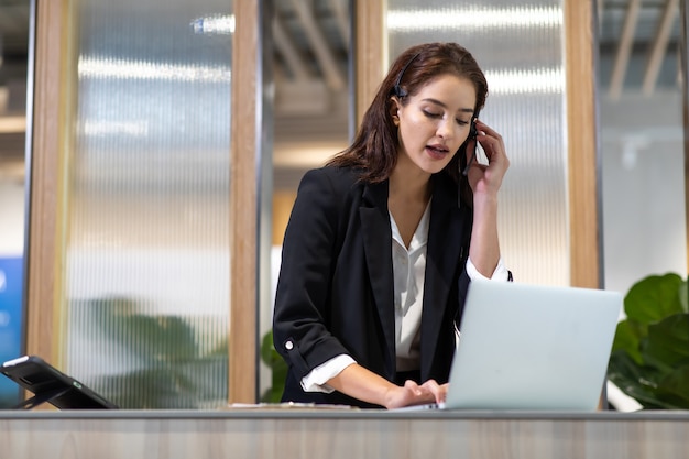 Attractive business woman Asian in suits and headsets are smiling while working with computer  