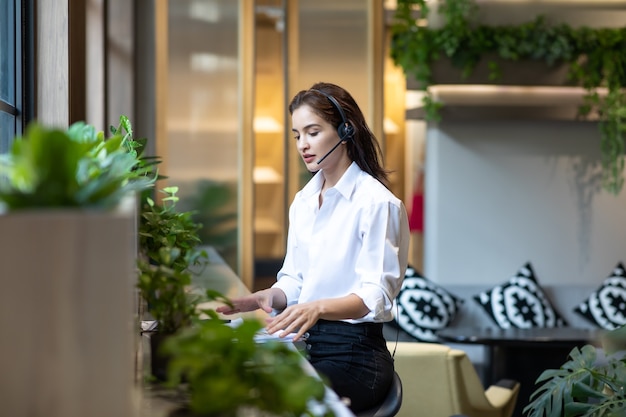 Attractive business woman Asian in suits and headsets are smiling while working with computer  