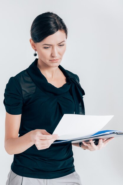 Attractive business woman holding a folder with documents on a gray background