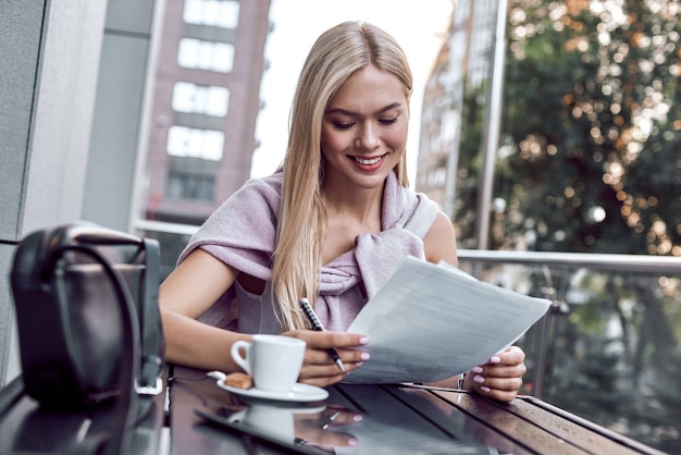 Attractive business woman reading newspapers at city cafe