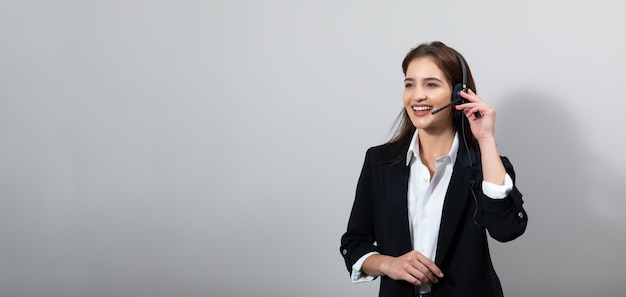 Foto attraente donna d'affari in giacca e cuffia sorride mentre lavora in isolamento
