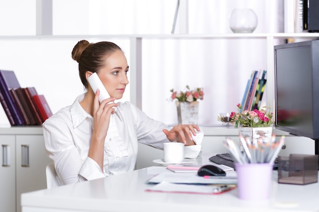 Attractive business woman talking on the phone in the office.