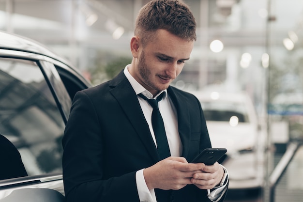 Attractive businessman buying new automobile at the dealership